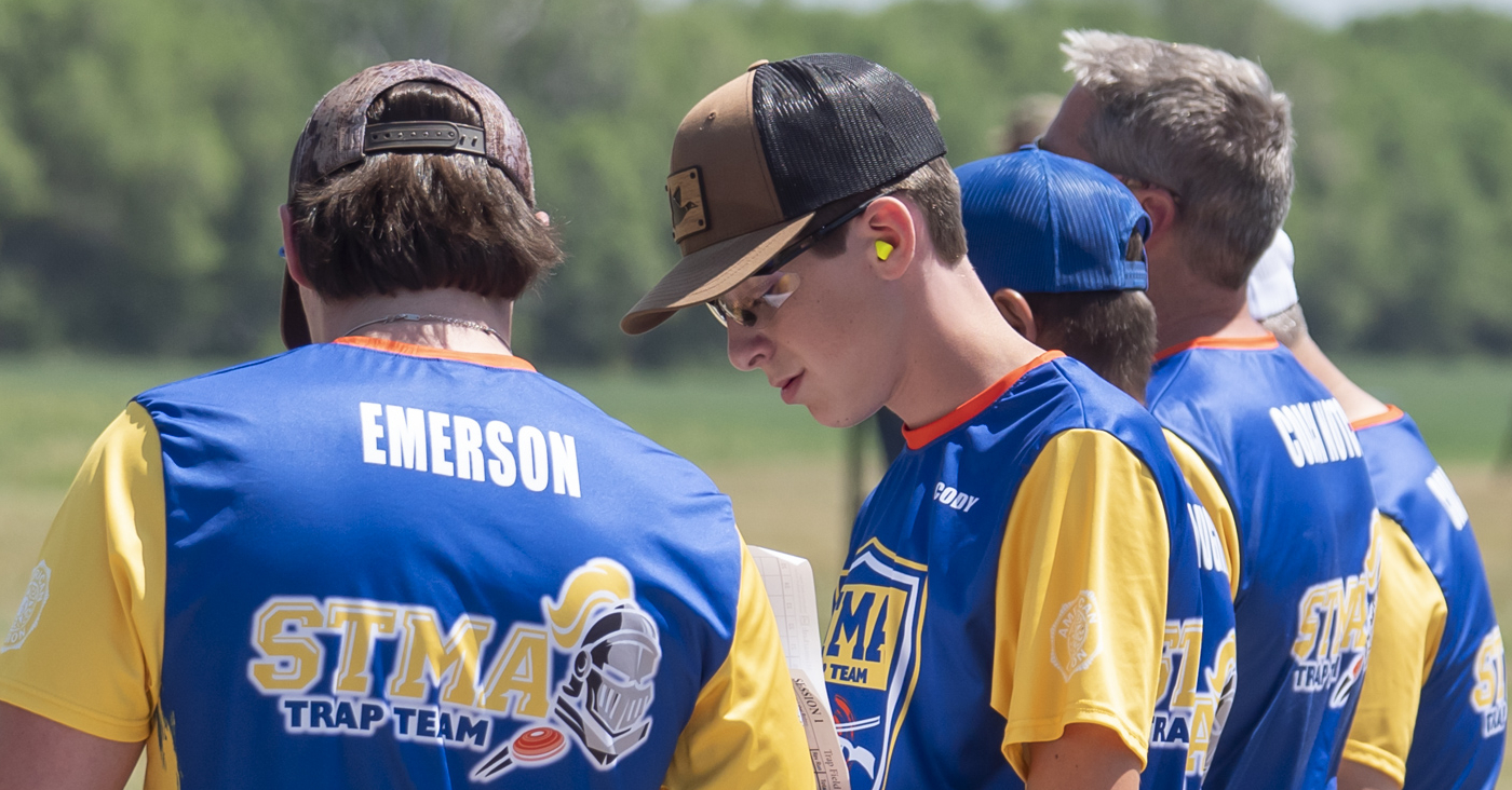 A group of men in blue and yellow shirts are standing in a field.